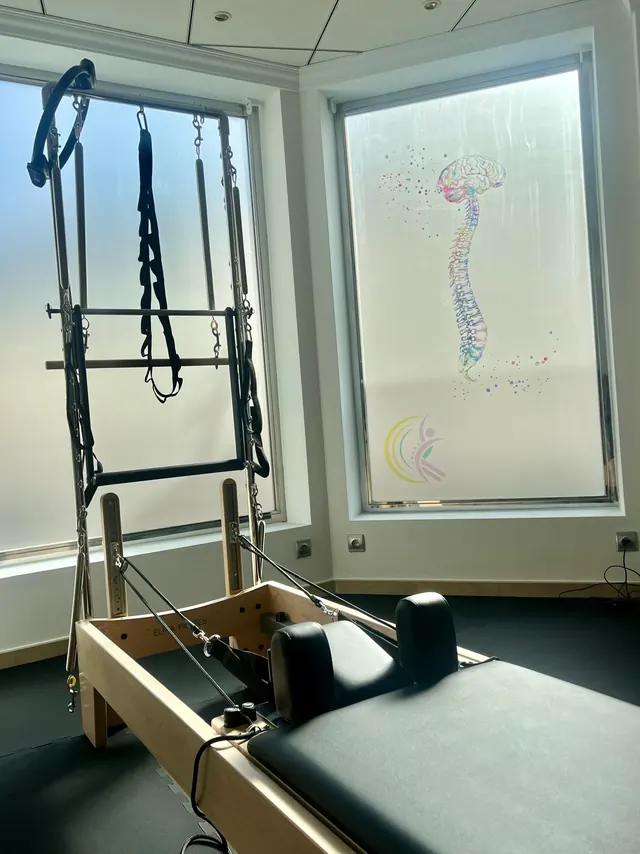 Máquina Reformer con torre junto a una ventana decorada con una columna vertebral y el logotipo de Chus & Cou